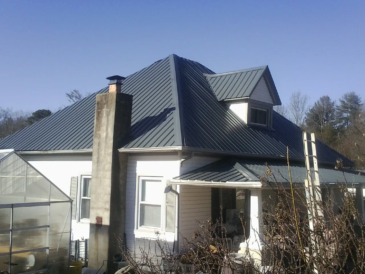 Dark blue standing seam metal roof on a white farmhouse with dormer — Slate & Tile Roof Repair by Roofing Brothers in Branford