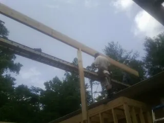 Carpenter setting a ridge beam over a new addition frame — Ice Dam Removal by Roofing Brothers in Branford