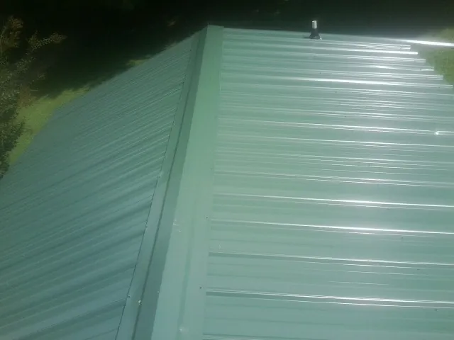 New green metal panels meeting at the ridge of a roof — Flat Roof Repair work by our crew in Branford
