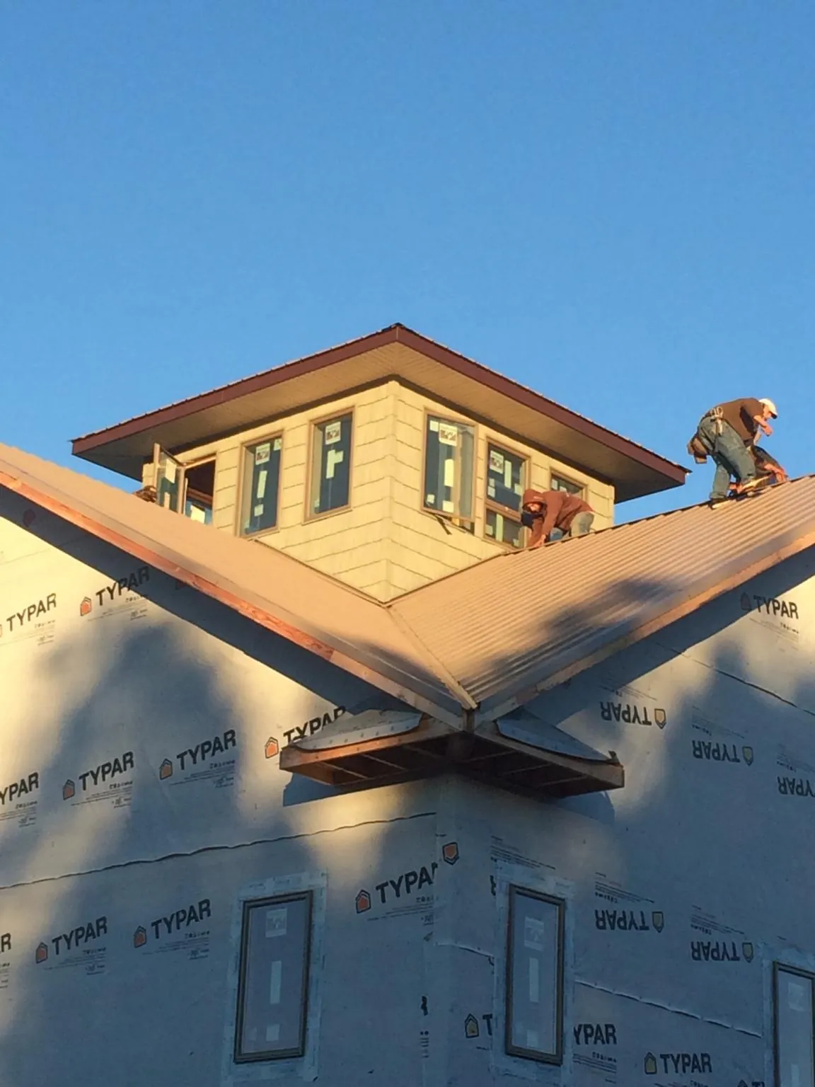 Roofers working around a rooftop cupola on a new metal roof at sunset — Roof Waterproofing in Branford by Roofing Brothers